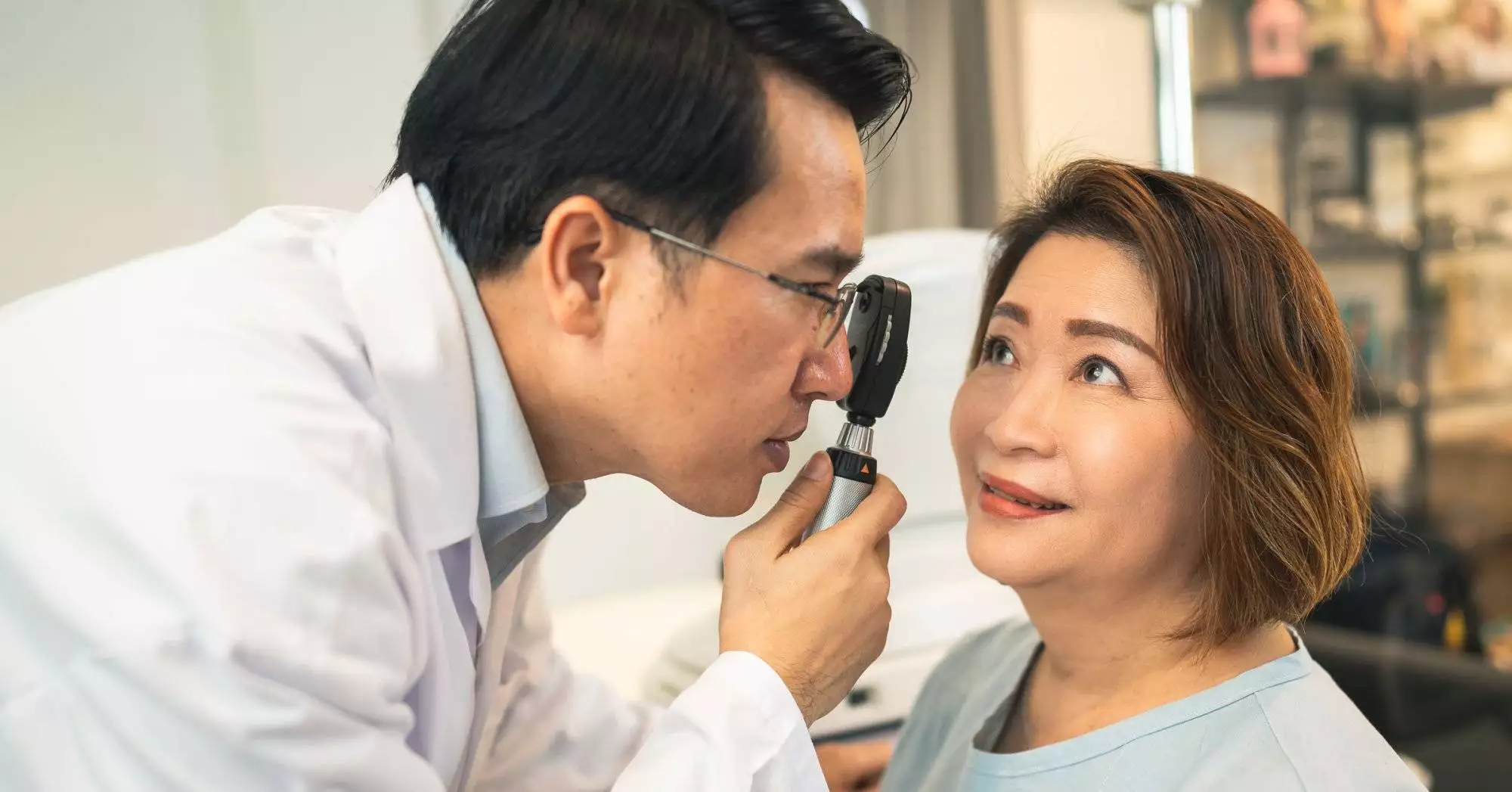 optometrist checking eyes condition of client before check eyesight in optical store